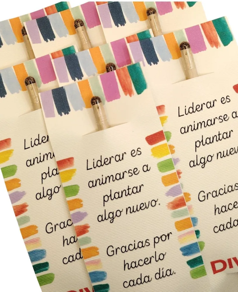 Lápices plantables de madera con una cápsula de semillas con tapón de corcho en la punta, sobre tarjetas impresas.