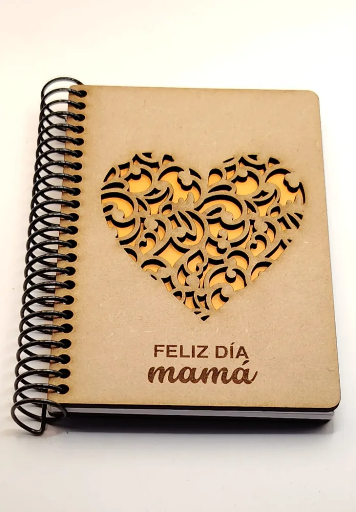 Libreta de madera con un corazón calado a láser y papel amarillo asomando por detrás.