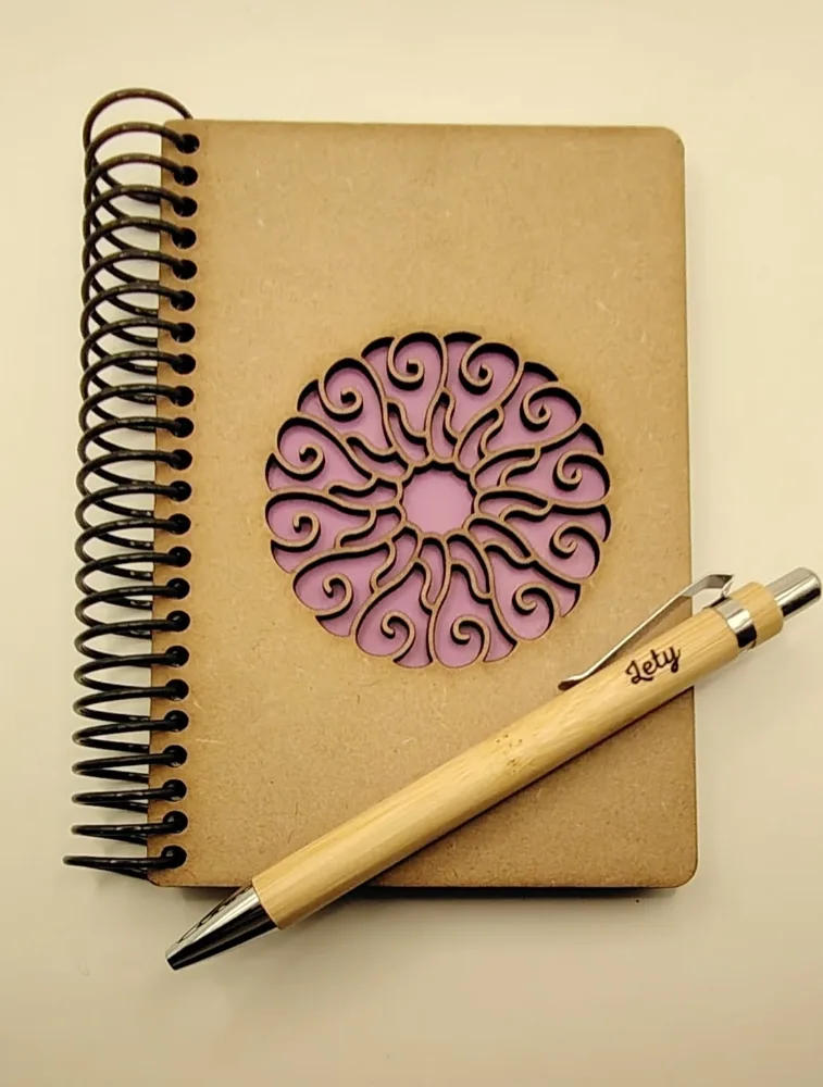Libreta de madera con una mandala calada y una lapicera de bambú grabada con un nombre.