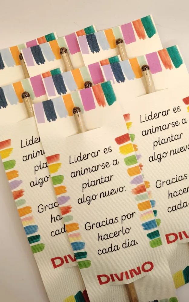 Lápices plantables de madera con una cápsula de semillas con tapón de corcho en la punta, sobre tarjetas impresas.