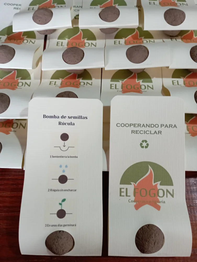 Bombas de semillas en sobres de papel con una ventana redonda por la que asoma la bomba, y la cara con las instrucciones de uso.