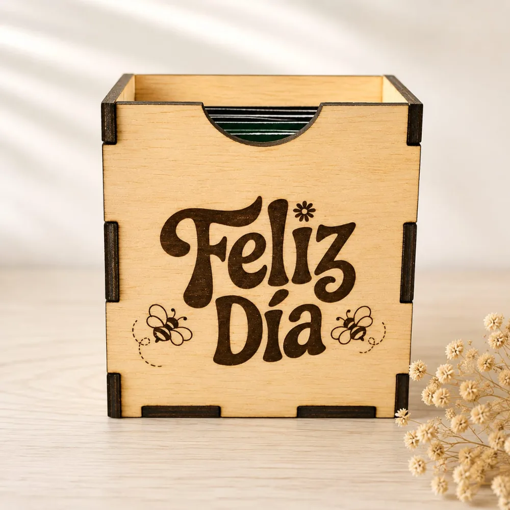 Cajita de madera encastrada, grabada con «Feliz día» y dos abejas, con sobres de té asomando por arriba.