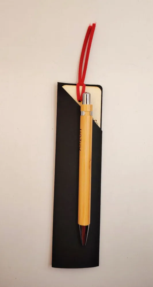 Marcalibros con tiento rojo guardado en un sobre negro, con una lapicera de bambú por delante.
