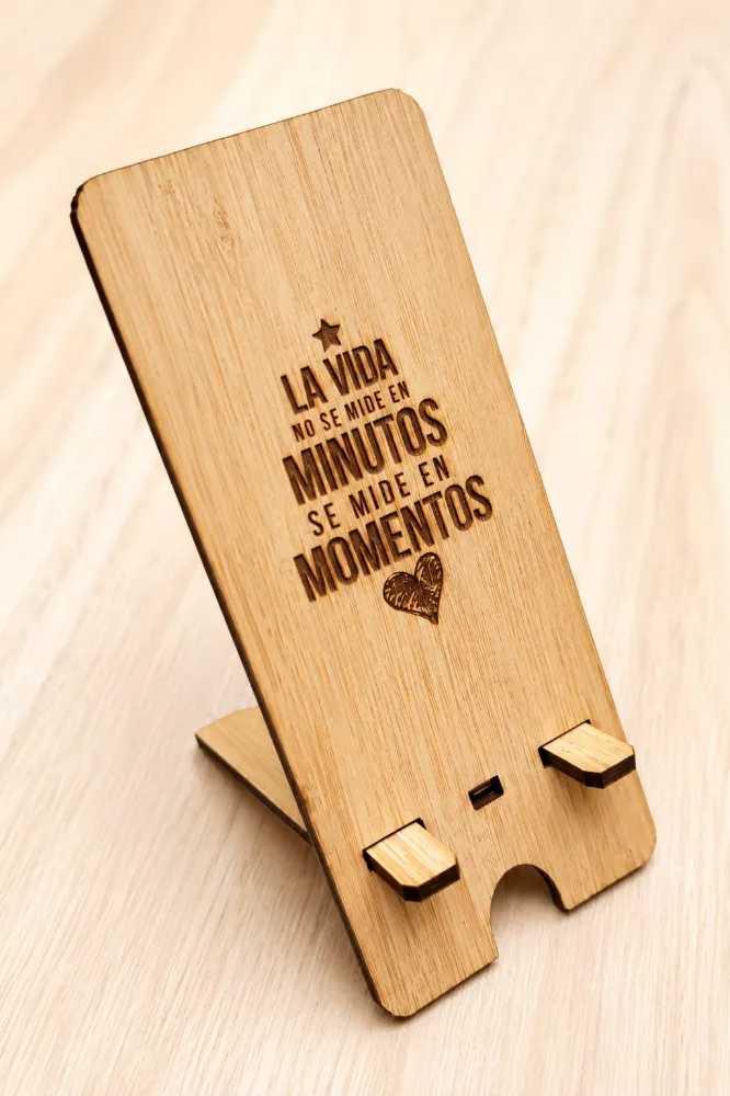 Porta celular de madera encastrado, grabado con la frase «La vida no se mide en minutos, se mide en momentos» y un corazón.