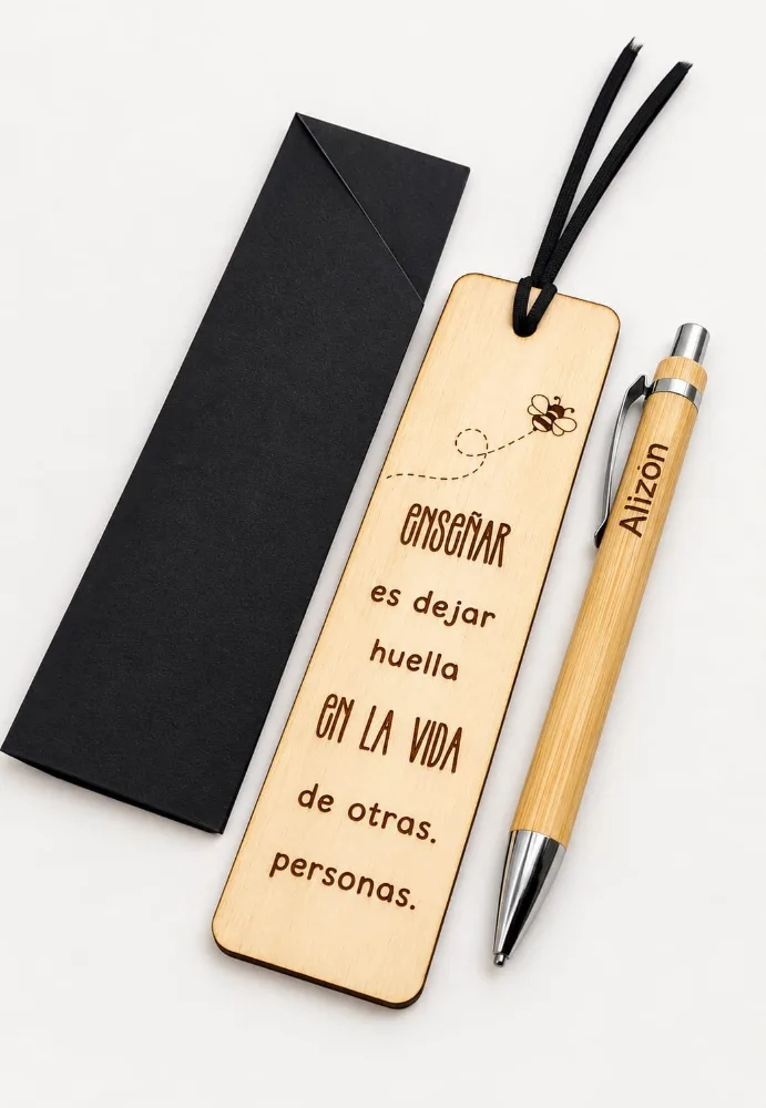 Marcalibros de madera con tiento negro, grabado con una abeja y la frase «Enseñar es dejar huella en la vida de otras personas», junto a un sobre negro y una lapicera de bambú grabada.